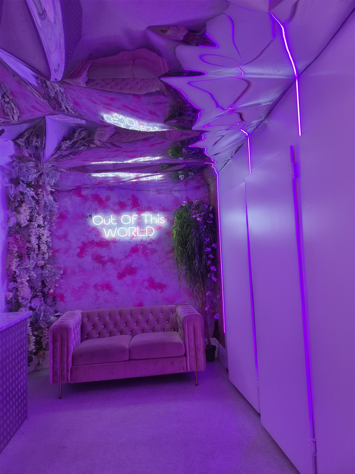 Neon lighting, mirrored ceiling and a pink sofa.