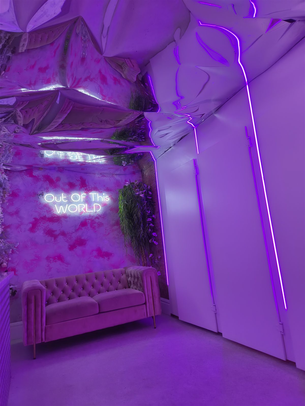 Purple-lit seating corner beneath the Out Of This World sign.